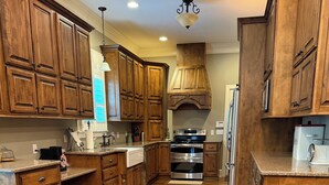 Una cocina con armarios de madera, electrodomésticos de acero inoxidable y piso de madera pulida.