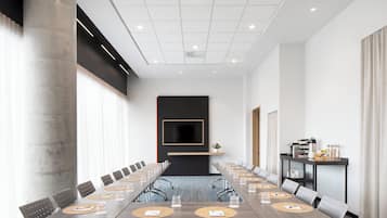 Una sala de conferencias con una larga mesa, sillas, una pantalla de televisión y una estación de café.