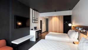 Habitación de hotel moderna con televisión de pantalla plana, escritorio, banca, dos camas y un revestimiento de pared de madera.