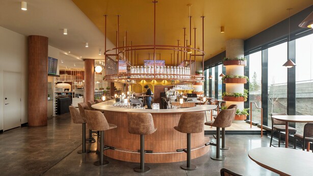 Zona de bar con barra circular, taburetes y vistas al exterior.