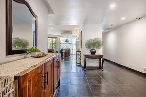 A hallway with a wooden cabinet, a mirror, and a potted plant. - Spacious La Perla Condo with Terrace and Views (Tamarindo)