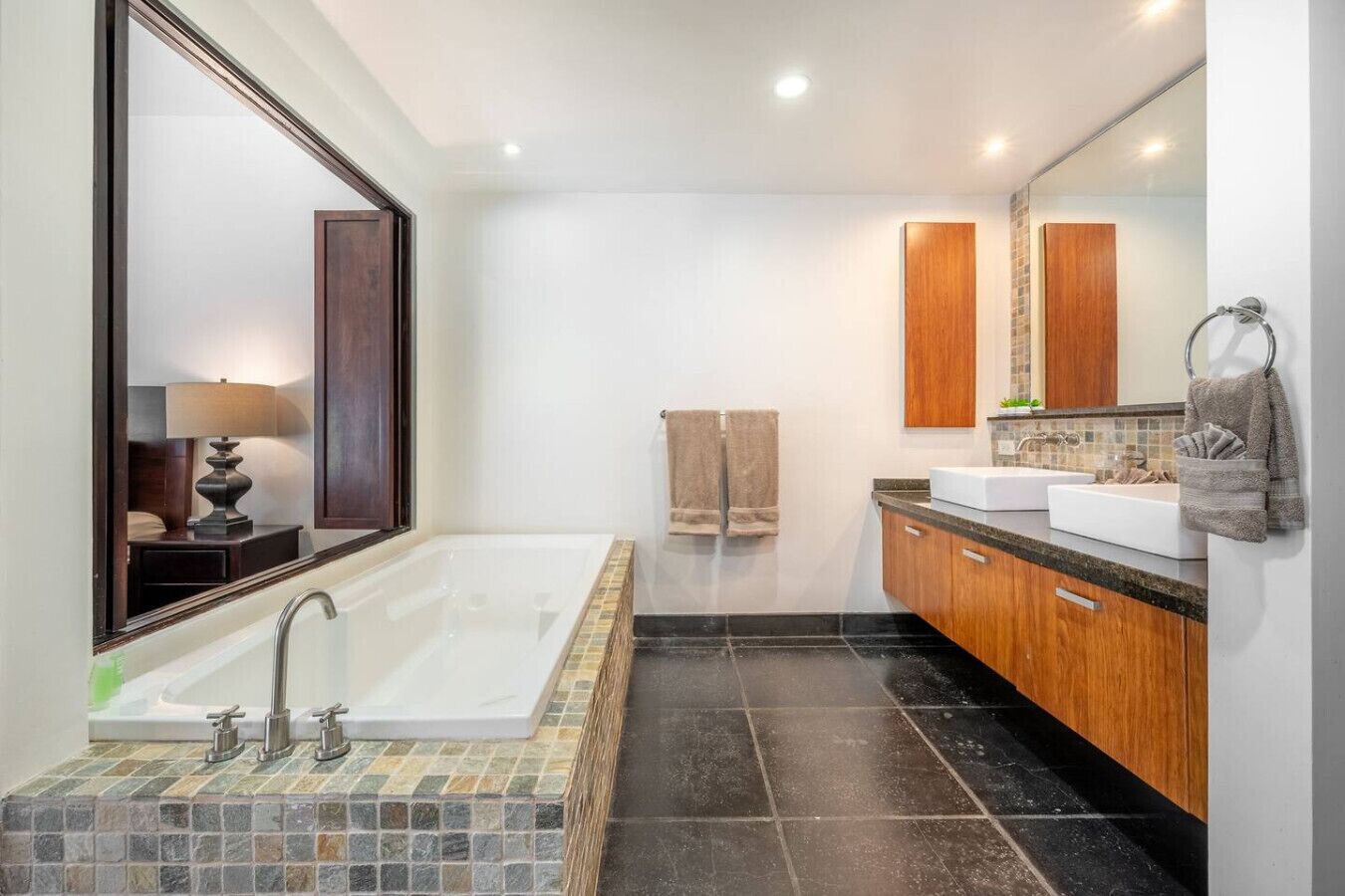 Een moderne badkamer met een groot bad, twee wastafels en een spiegel.