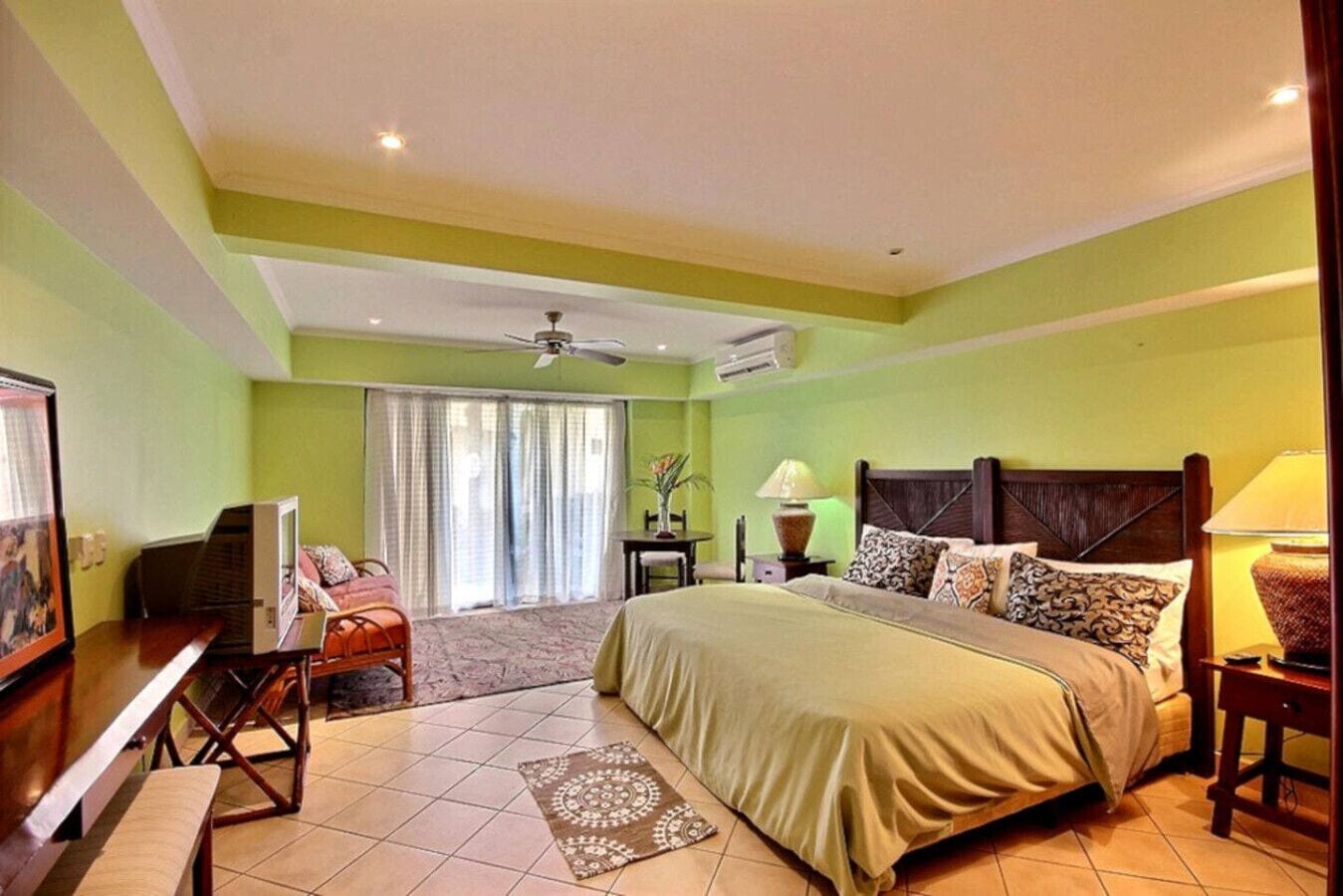 A hotel room with a bed, a desk, a chair, a TV, and a window with curtains.