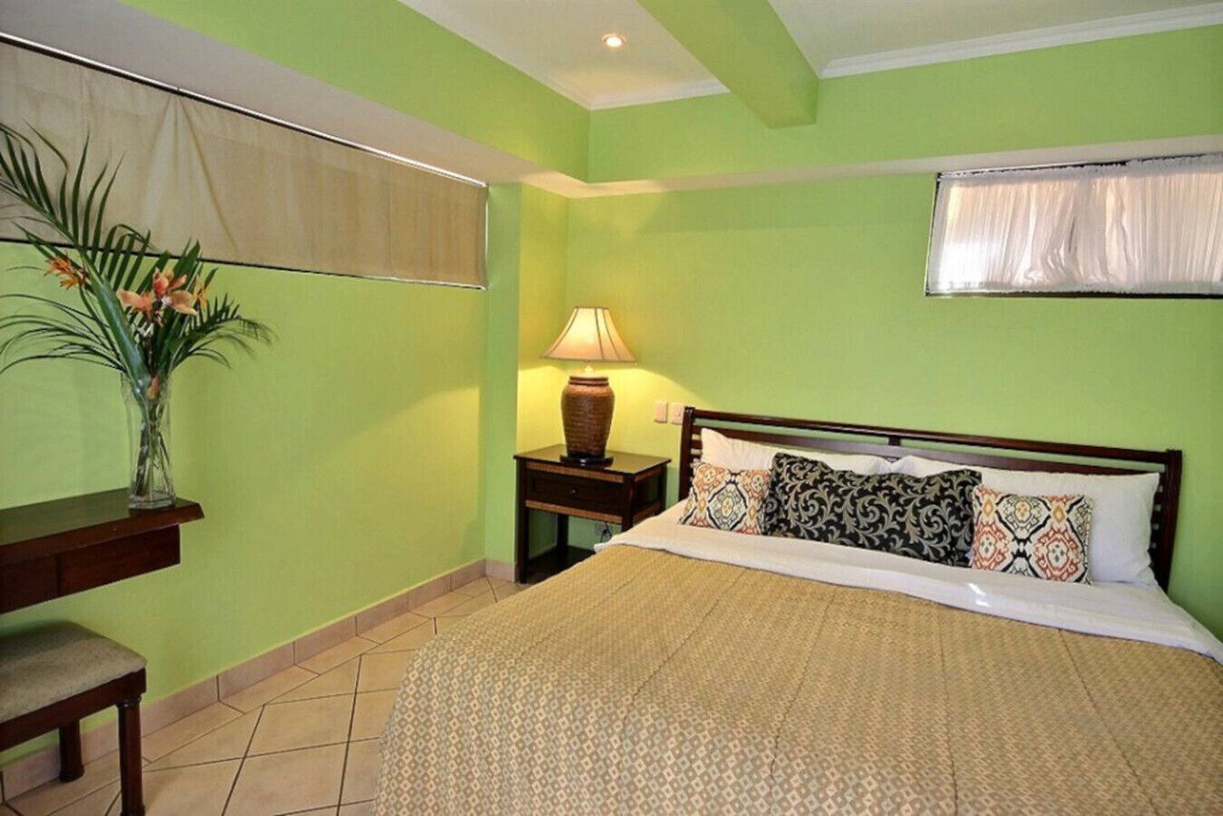 A bedroom with a bed, a nightstand, a lamp, and a vase with flowers.