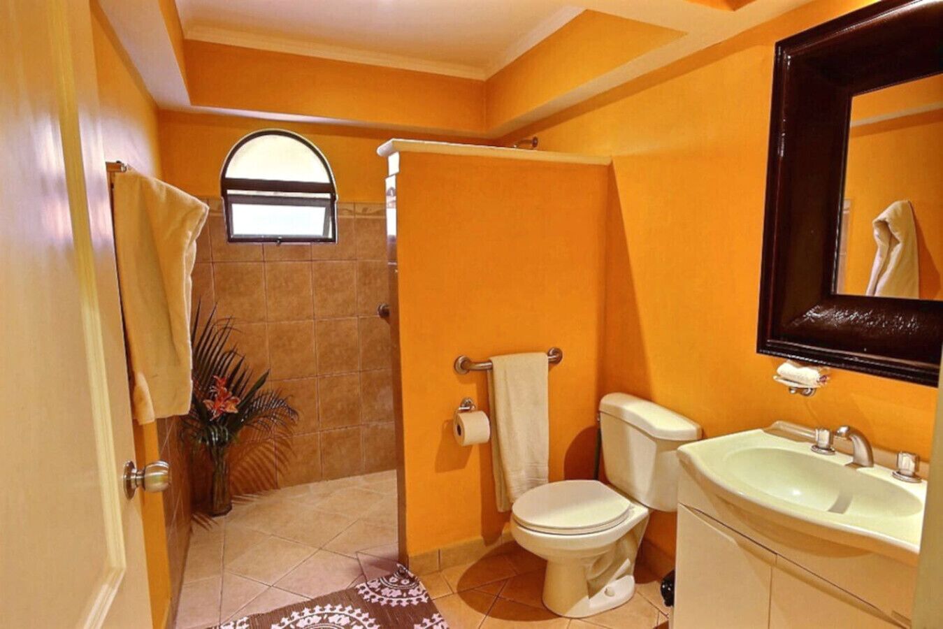 Une salle de bain avec des toilettes blanches, un lavabo et un miroir.