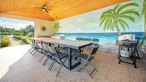 An outdoor dining area with a beach mural, a ceiling fan, and a portable grill. - Villa Sol y Mar Shared Pool 2 miles to Beach (Potrero)