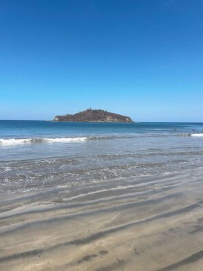 A beach with a sandy shore and a small rocky island in the distance. - Villa Sol y Mar Shared Pool 2 miles to Beach (Potrero)