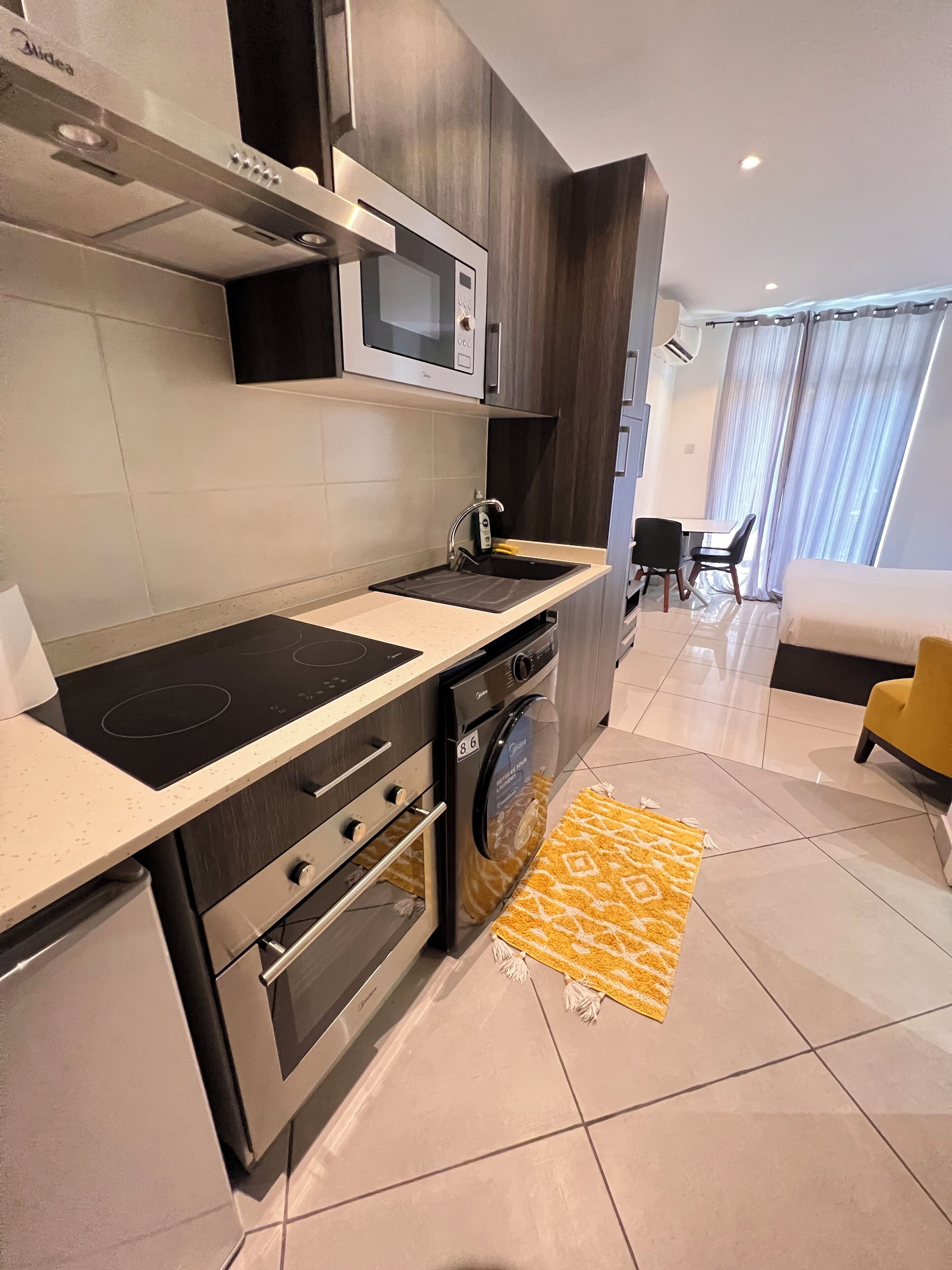 A modern kitchen with a built-in microwave, oven, and dishwasher. There is a dining area with a table and chairs.