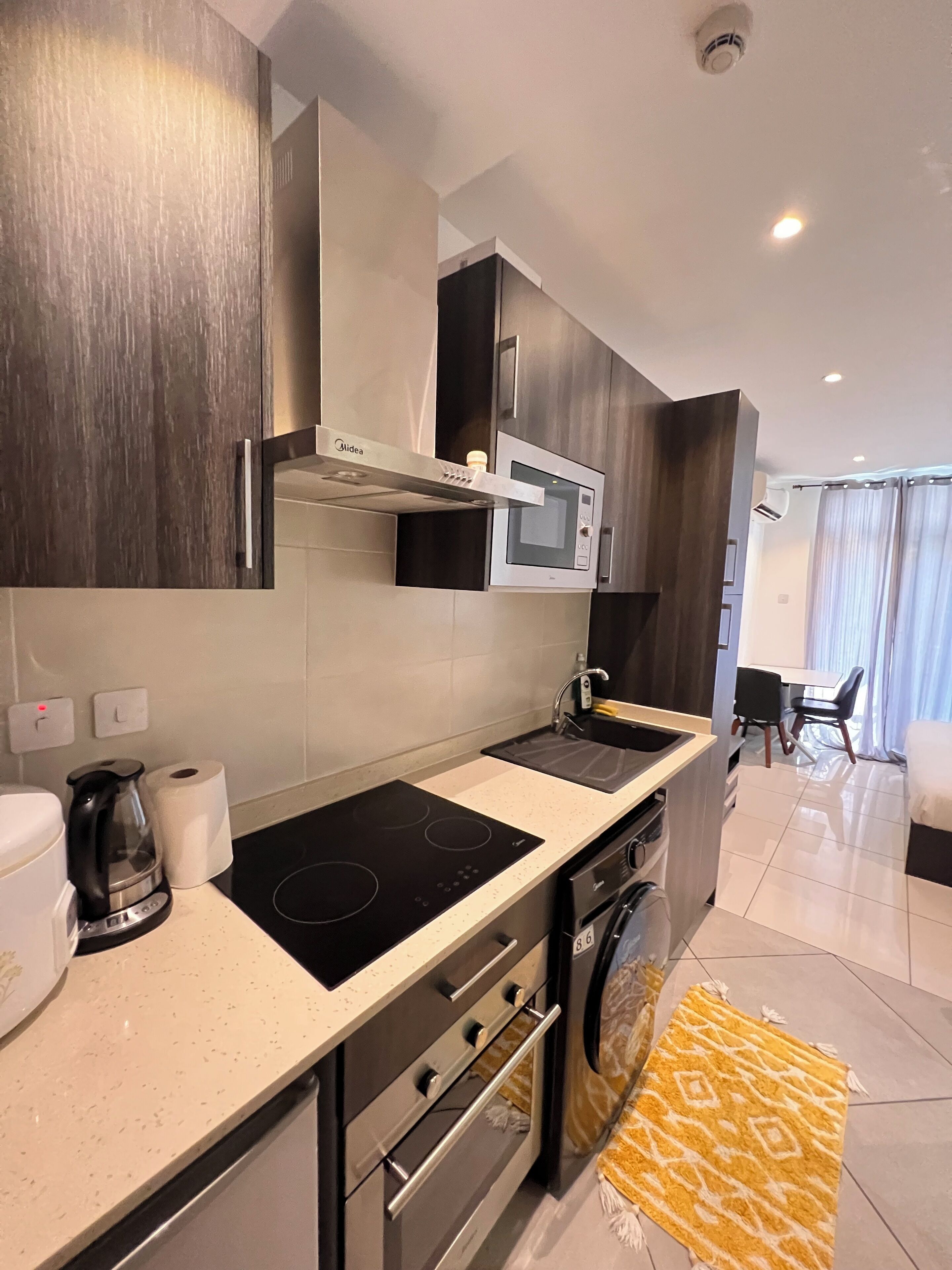 A modern kitchen with a built-in microwave, stove, and oven. There is a coffee maker and a roll of paper towels on the counter.