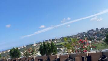 An outdoor seating area with tables and chairs, overlooking a cityscape.