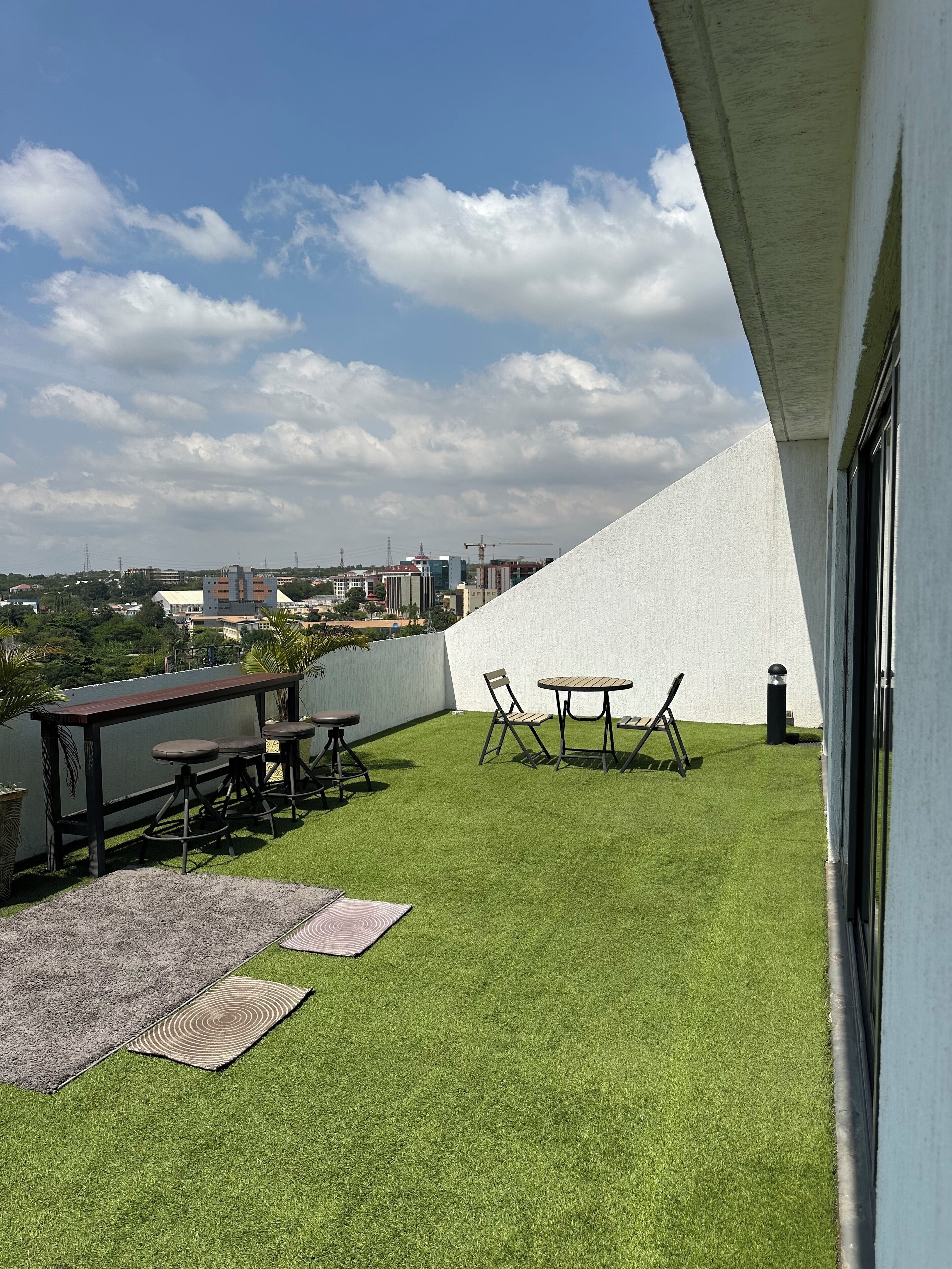 A rooftop terrace with artificial grass, a wooden table, and chairs.