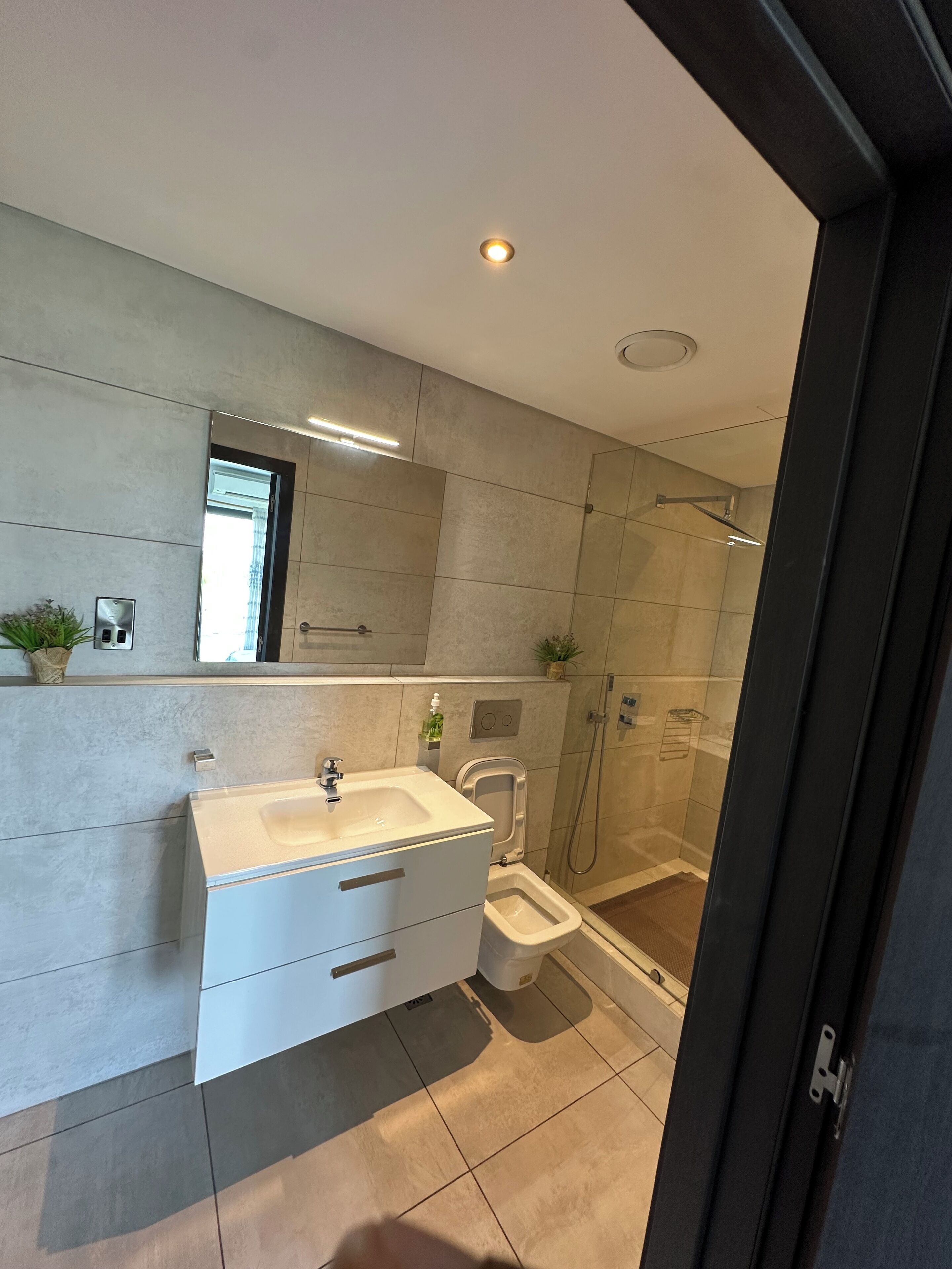 A modern bathroom with a sink, mirror, and shower.