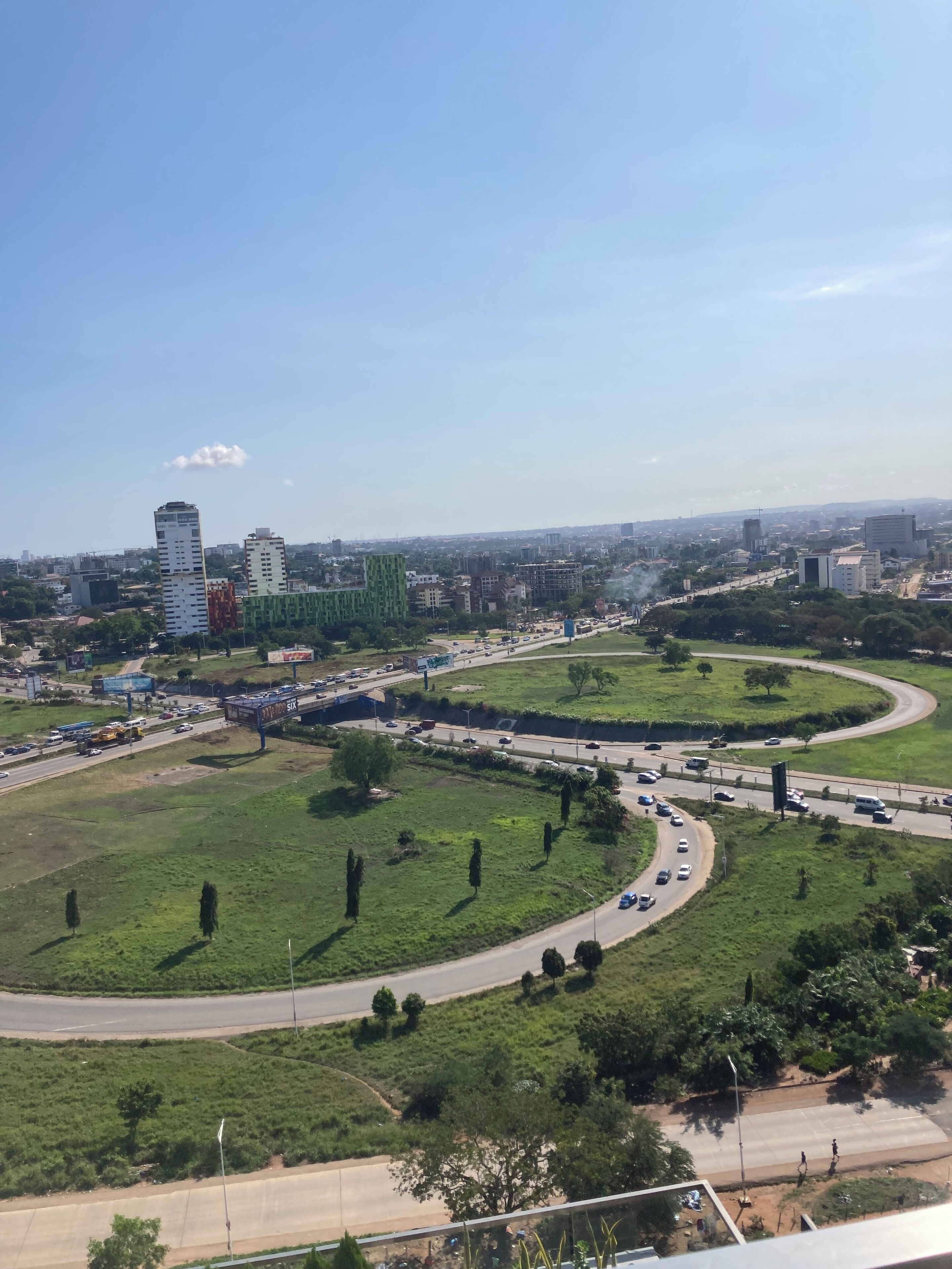 A cityscape with a highway, green areas, and buildings.
