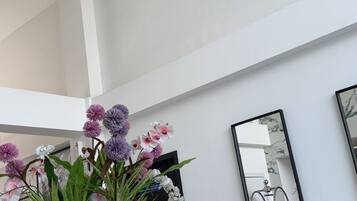 A modern interior with a dining area, a large mirror, and decorative orchids.