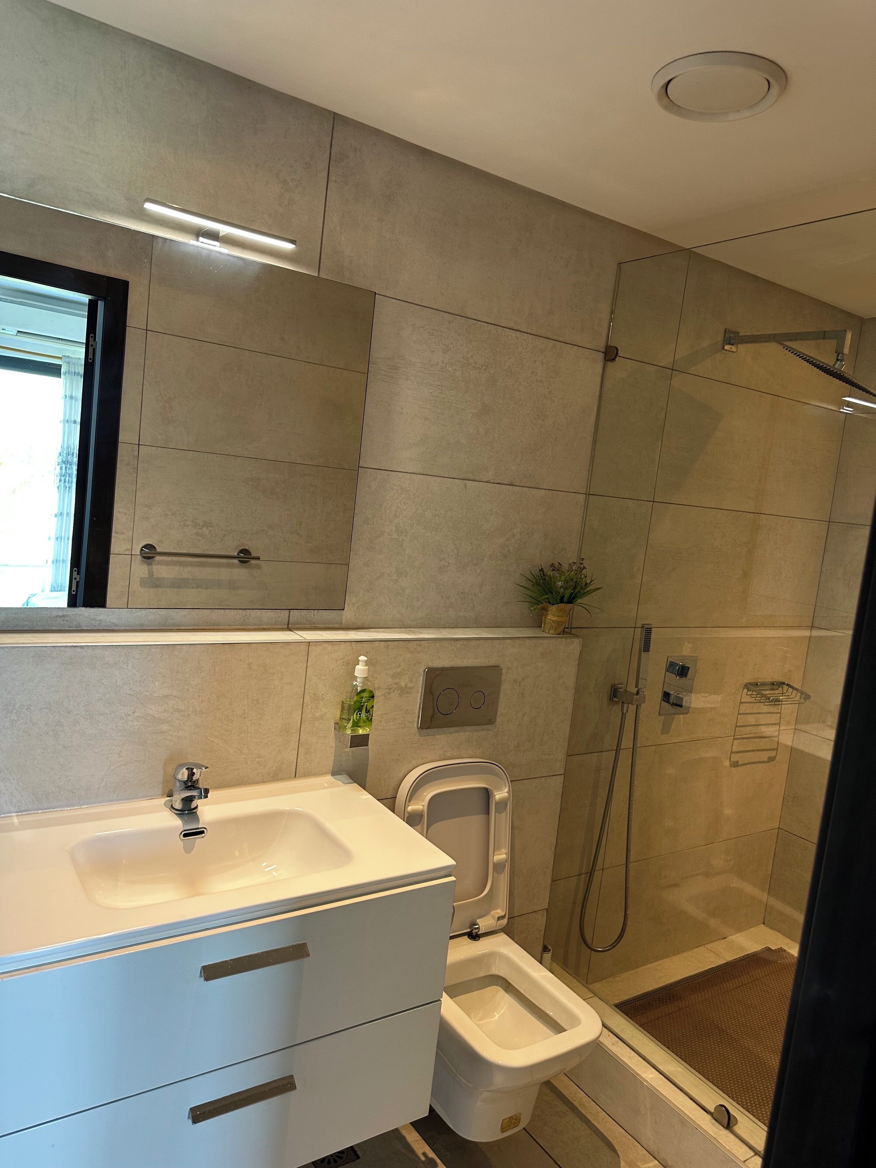 Ein modernes Badezimmer mit einem großen weißen Waschbecken, einem Bidet und einer Duschkabine.