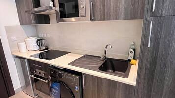 A modern kitchen with dark wood cabinets, a stainless steel microwave, a built-in oven, a dishwasher, and a sink with a faucet.