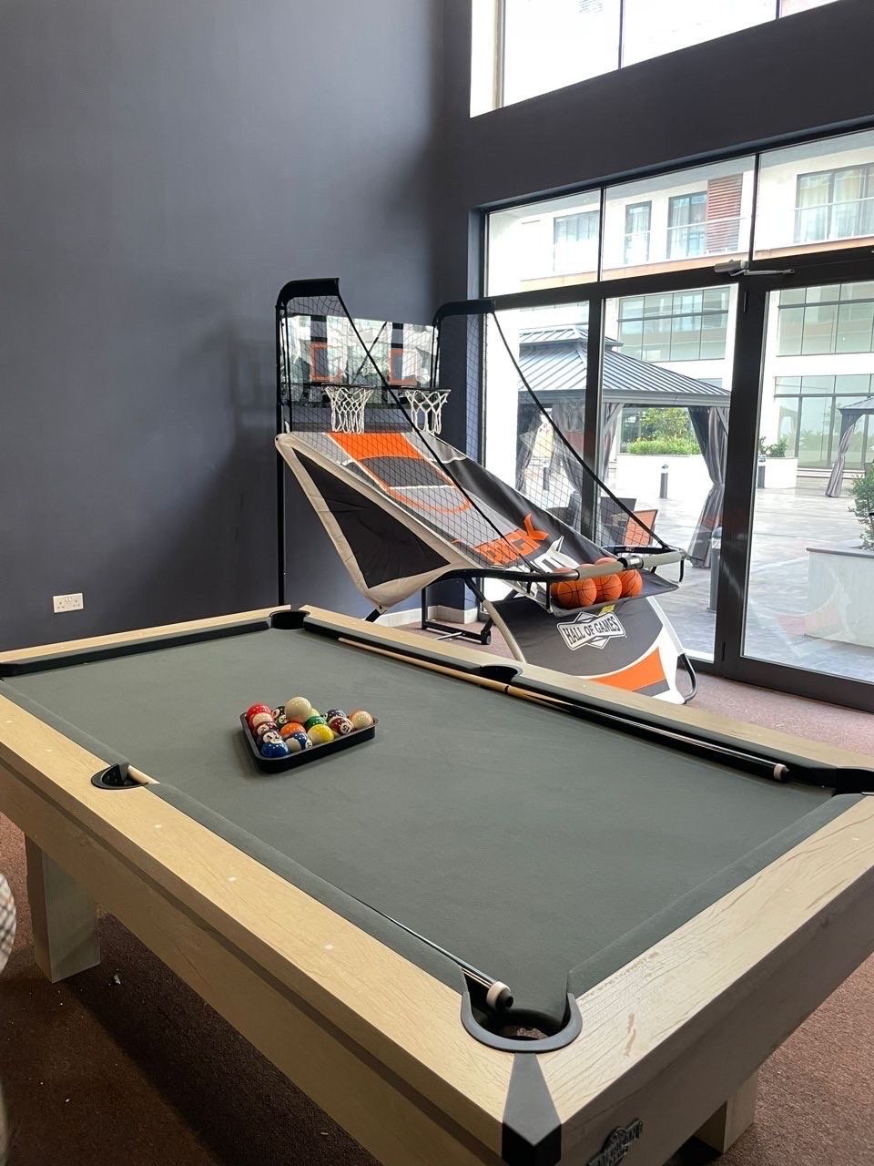 Una mesa de billar con aro de baloncesto y un atril para bolas de billar.