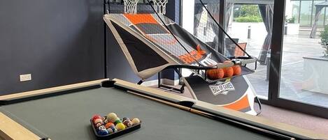 A pool table with a basketball hoop and a rack of billiard balls.