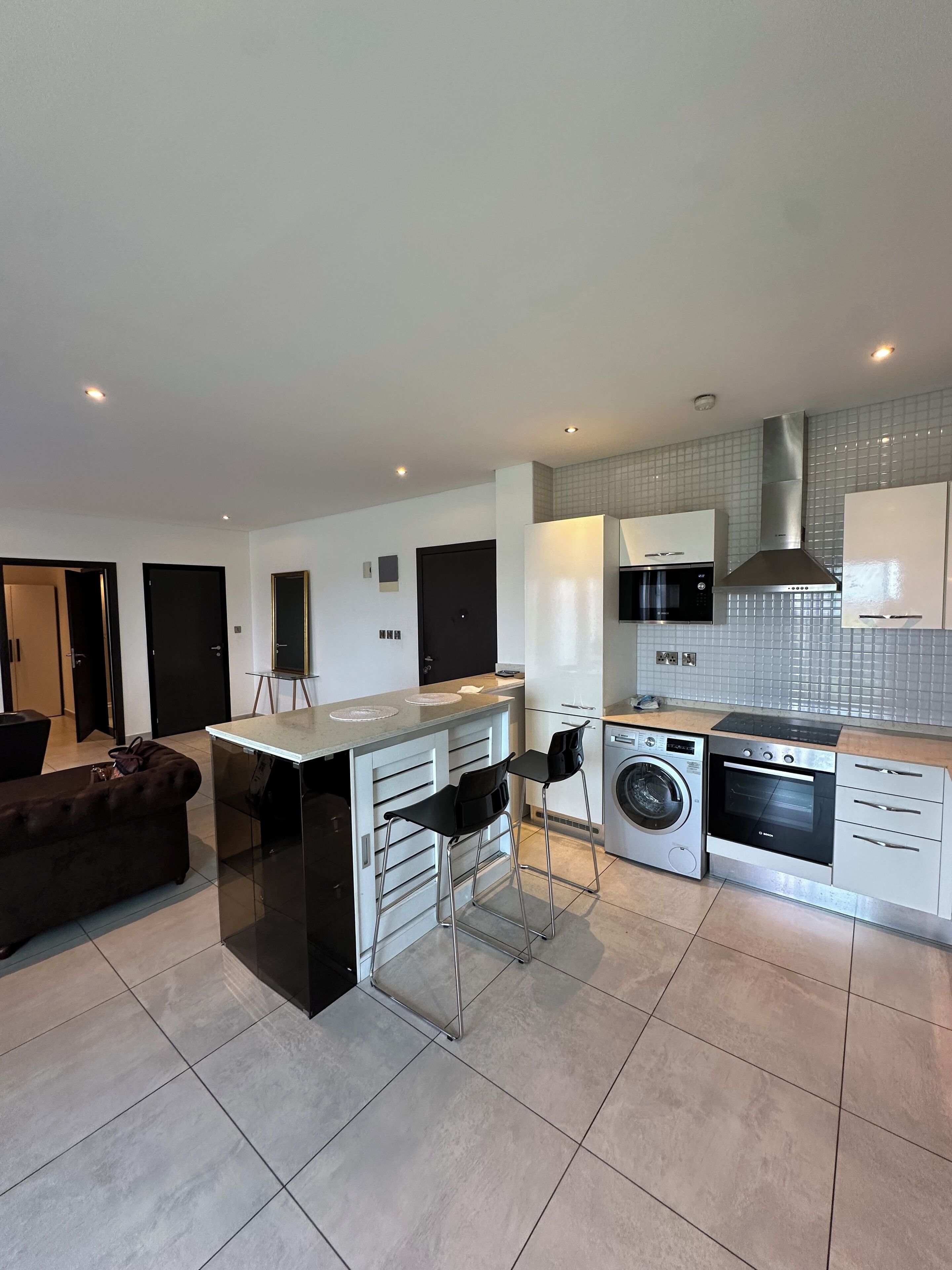 A modern kitchen with a central island, built-in appliances, and a dining area with a sofa.