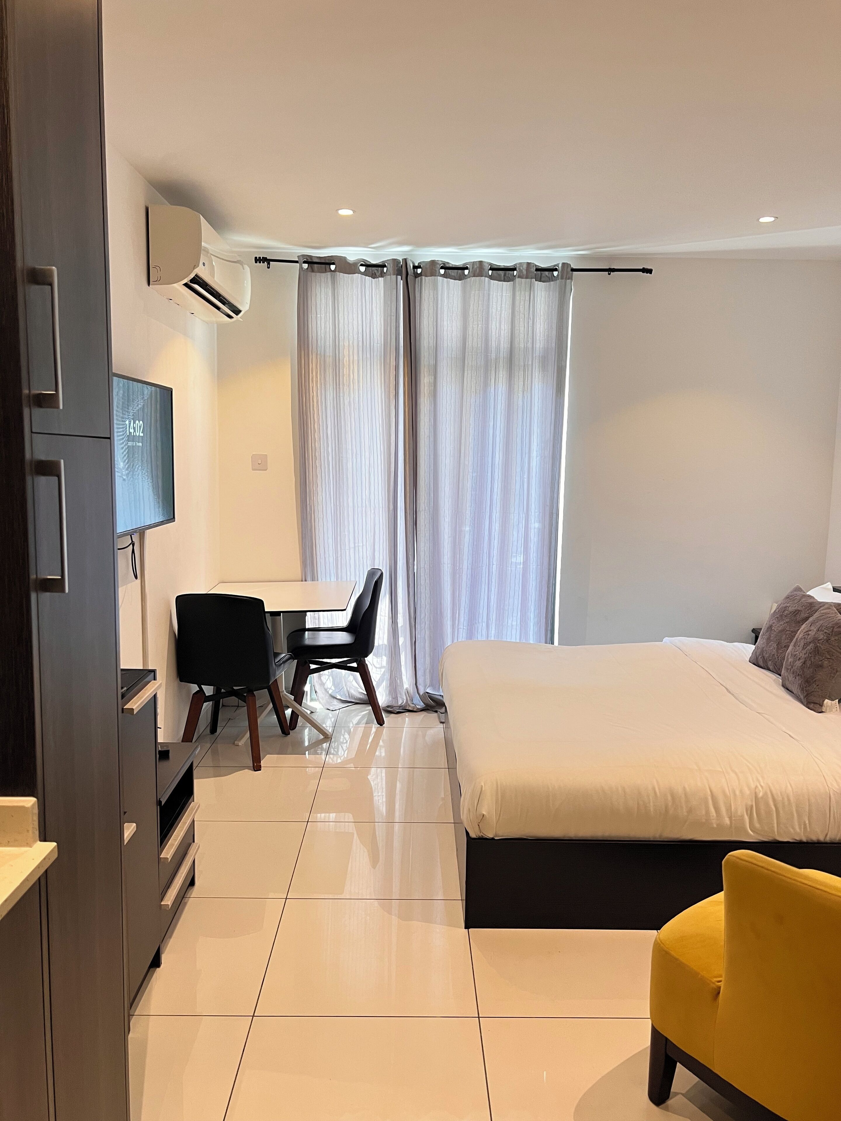 A modern hotel room with a bed, a desk, a chair, and a TV.