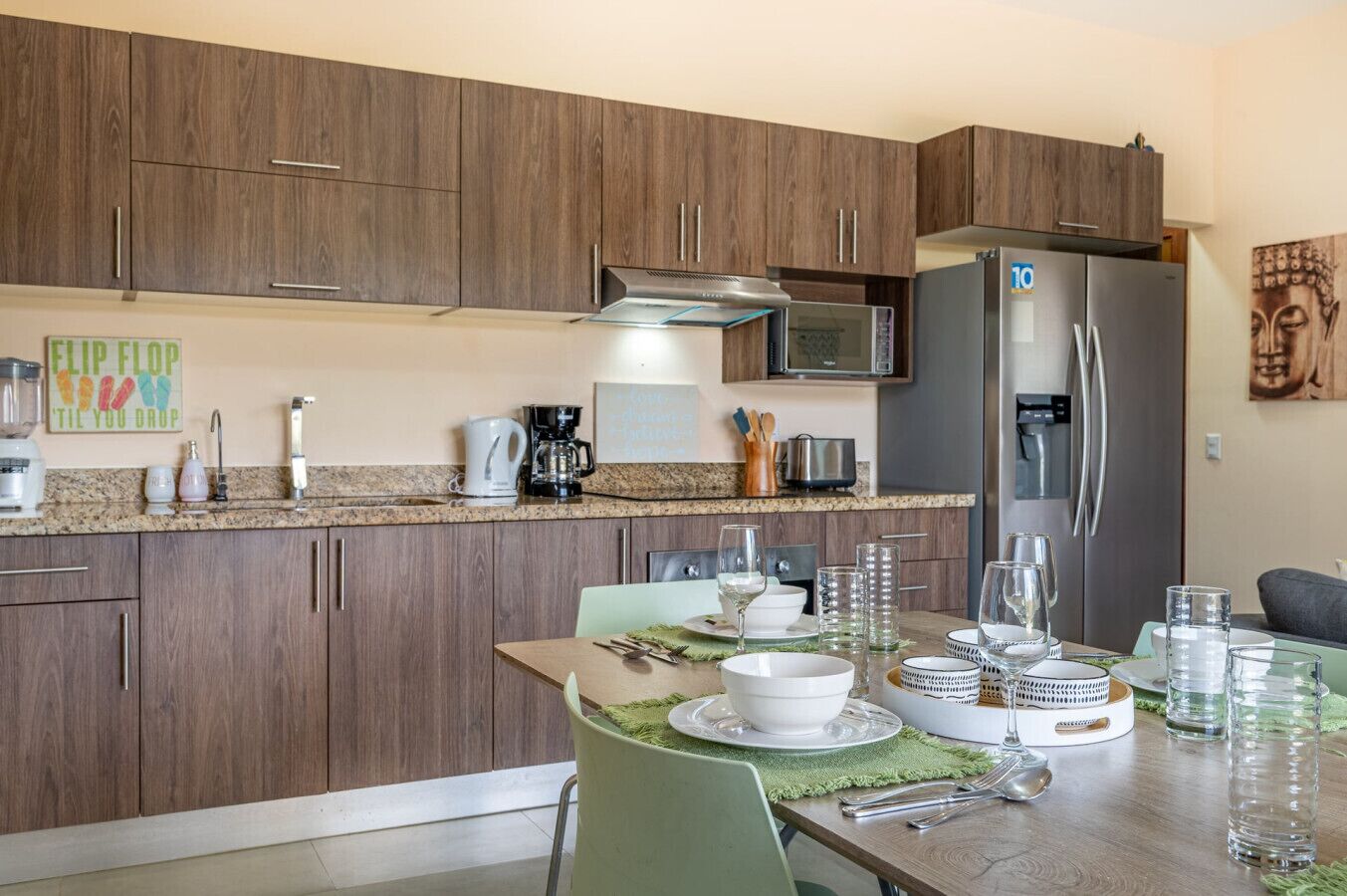 Una cocina moderna con armarios de madera, un refrigerador de acero inoxidable y un comedor listo para una comida.