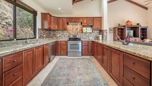 A kitchen with wooden cabinets, a granite countertop, a built-in oven, and a stone backsplash. - Luxury Living at Villas Catalina #13 (Potrero)