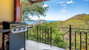 A balcony with a grill and a view of a coastal landscape. - Luxury Living at Villas Catalina #13 (Potrero)
