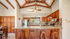 A spacious kitchen with wooden cabinets, a granite countertop, and a central island with stools. - Luxury Living at Villas Catalina #13 (Potrero)
