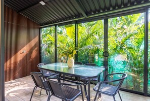 A modern indoor space with a glass wall, a round table, and black chairs. - Moani Punta Uva Lodge 5 min Walk to beach (Talamanca)