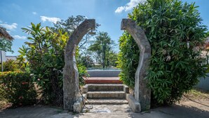 Un sentiero conduce all'ingresso di un edificio, con archi in pietra e una scalinata in cemento.