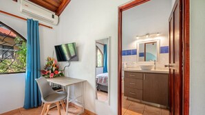 Una stanza con scrivania, sedia, televisione e bagno con specchio e lavandino.