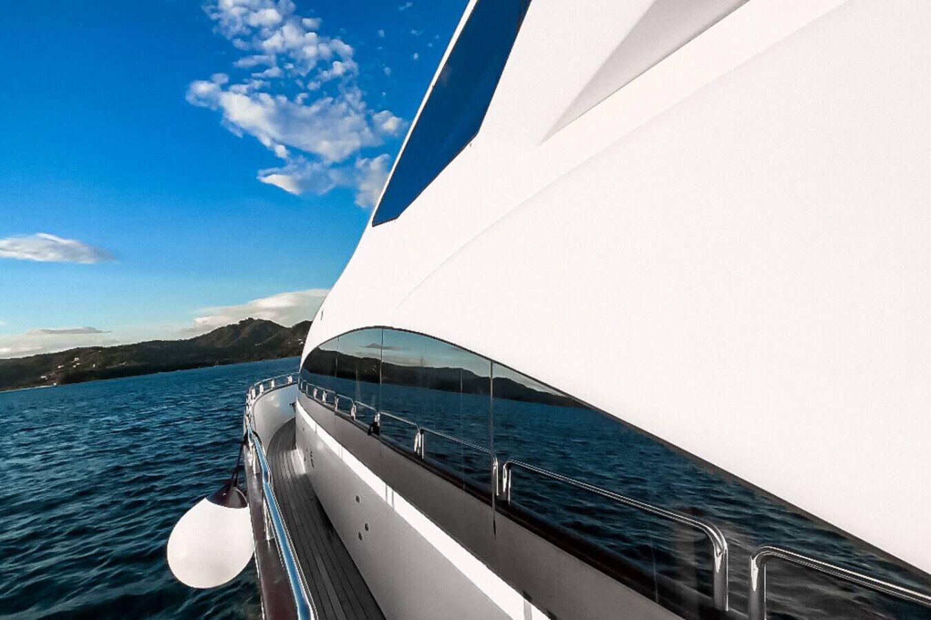 Un yate moderno con un exterior blanco y elegante, cubierta curva y barandilla de vidrio.