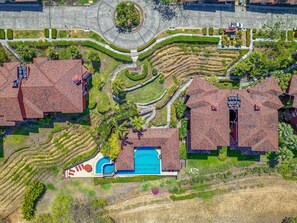 A residential area with multiple houses, a central circular driveway, and a swimming pool. - Sunshine Getaway- Lovely Golf Front Villa (Brasilito)