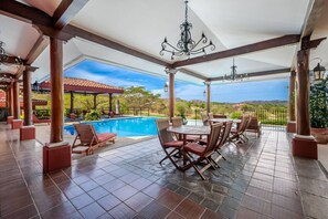 A covered outdoor area with a pool, wooden furniture, and a view of the landscape. - Sunshine Getaway- Lovely Golf Front Villa (Brasilito)