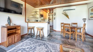 A modern kitchen with wooden cabinets, a bar area, and a dining set. - Cultural Charm and Ocean Views in Playa Flamingo (Playa Flamingo)
