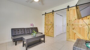 A modern living room with a sofa, coffee table, and a sliding barn door. - Steps to Pompano Beach: Couple's Retreat w/ Patio! (Pompano Beach)