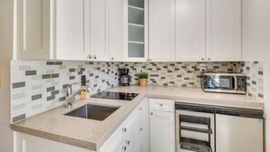 A kitchen with white cabinets, a microwave, a coffee maker, and a dishwasher. - Steps to Pompano Beach: Couple's Retreat w/ Patio! (Pompano Beach)