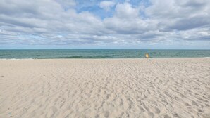 A wide sandy beach with gentle waves and a clear sky. - Steps to Pompano Beach: Couple's Retreat w/ Patio! (Pompano Beach)