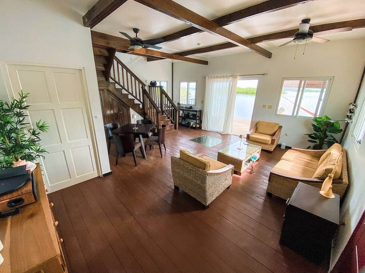 A spacious living area with a wooden floor, a staircase, and a dining area with a table and chairs.