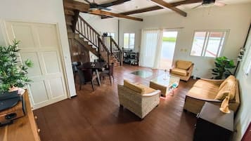 A spacious living area with a wooden floor, a staircase, and a dining area with a table and chairs.