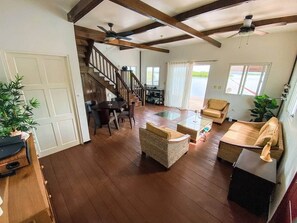 A spacious living area with a wooden floor, a staircase, and a dining area with a table and chairs.