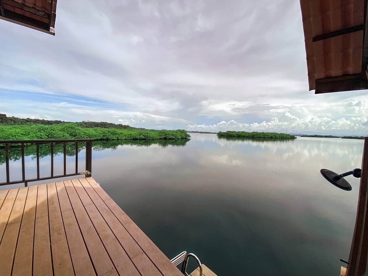 Une terrasse en bois offrant une vue sur une étendue d’eau paisible et une végétation luxuriante.