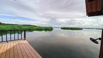 Une terrasse en bois offrant une vue sur une étendue d’eau paisible et une végétation luxuriante.