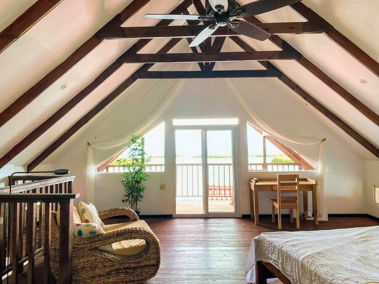 An attic bedroom with a sloped ceiling, a bed, a desk, and a chair.