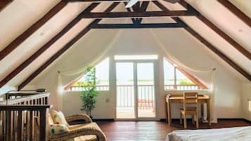 An attic bedroom with a sloped ceiling, a bed, a desk, and a chair.