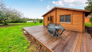 Eine Holzhütte mit einer Terrasse, einem Tisch und zwei Stühlen.