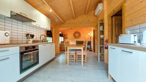 Eine moderne Küche mit weißen Schränken, einer Holzbalkendecke und einem Essbereich mit Tisch und Stühlen.
