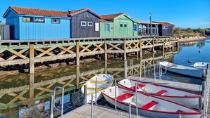 A waterfront with colorful wooden buildings, a dock, and several boats. - Appartement Proche Plage (Royan)