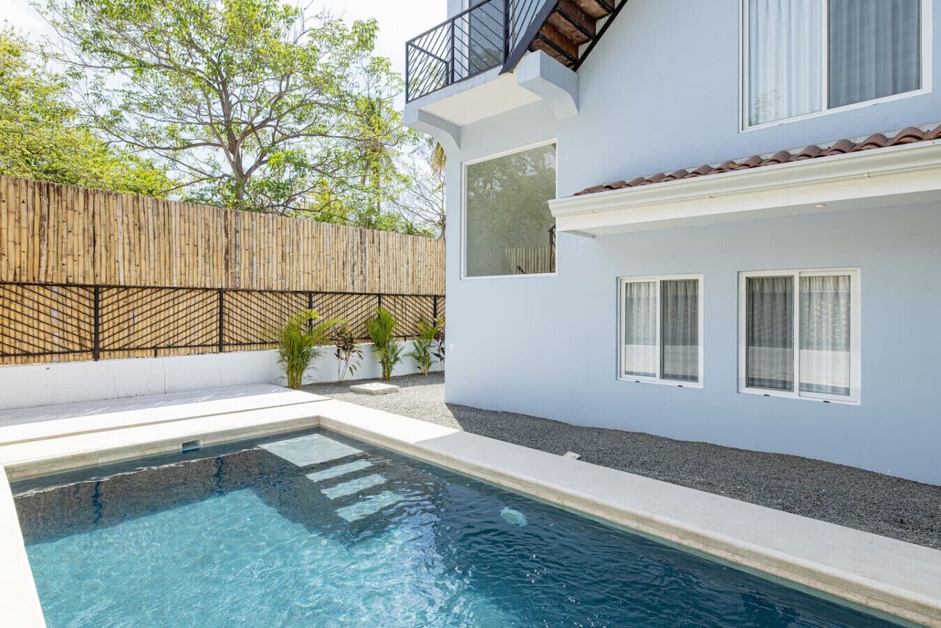 Ett modernt hus med en swimmingpool, ett trästaket och en balkong.