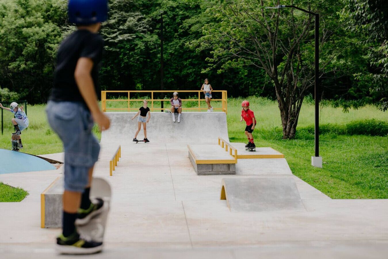 Un skatepark doté de rampes en béton et d’une barre en bois.